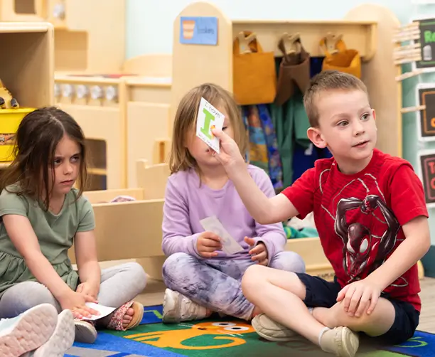 Little Boy Sitting On The Floor Holding Letter Card
