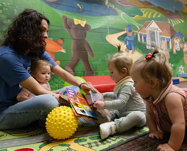 Woman Sitting On Rug Reading Book To Babies