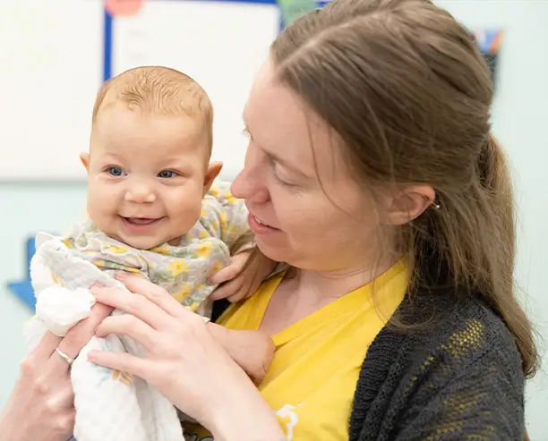 Woman Wearing Yellow Tshirt Holding Smiley Baby