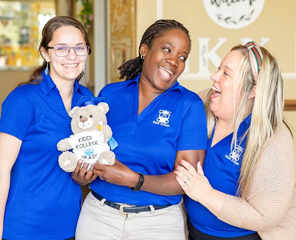 Smiling Preschool Teachers Holding Graduation Bear