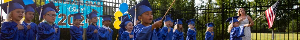 Preschool graduation ceremony with two students holding American flags.